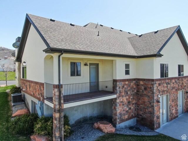 851 E Oak Ct Unit 28, Tooele, UT 84074 - rear view of house featuring central air condition unit, a shingled roof, stone siding, and stucco siding