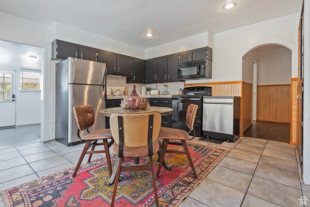 731 E Roosevelt Ave, Salt Lake City, UT 84105 - kitchen with wainscoting, black appliances, light tile patterned floors, arched walkways, and light countertops