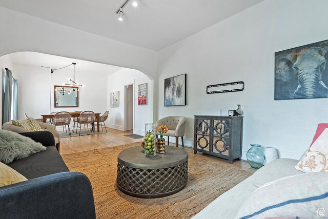 731 E Roosevelt Ave, Salt Lake City, UT 84105 - living area featuring arched walkways, baseboards, a notable chandelier, light wood-style floors, and rail lighting