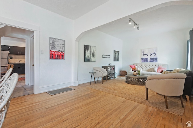 731 E Roosevelt Ave, Salt Lake City, UT 84105 - living area with track lighting, baseboards, arched walkways, and light wood-style flooring