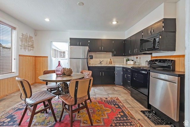 731 E Roosevelt Ave, Salt Lake City, UT 84105 - kitchen featuring a wainscoted wall, a sink, wood walls, dark cabinets, and black appliances