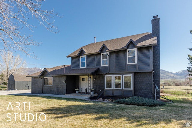 3116 N River Dr E, Eden, UT 84310 - view of front of house featuring a chimney, a front lawn, brick siding, and a mountain view