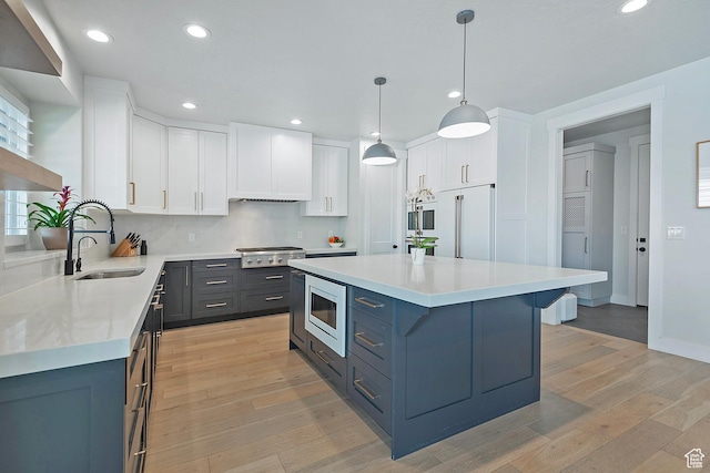 kitchen featuring built in microwave, recessed lighting, light countertops, a sink, and stainless steel gas cooktop