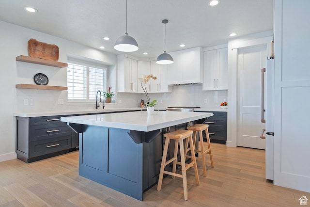 kitchen featuring light wood finished floors, a kitchen bar, and white cabinetry