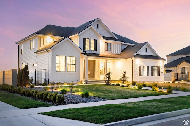 modern farmhouse featuring a front lawn, fence, and board and batten siding