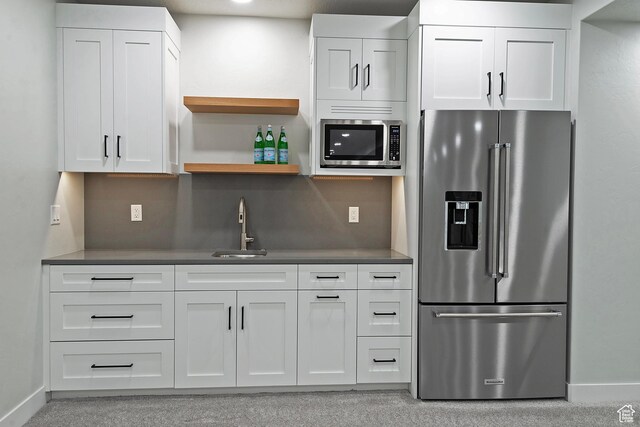 kitchen with white cabinets, appliances with stainless steel finishes, a sink, and dark countertops