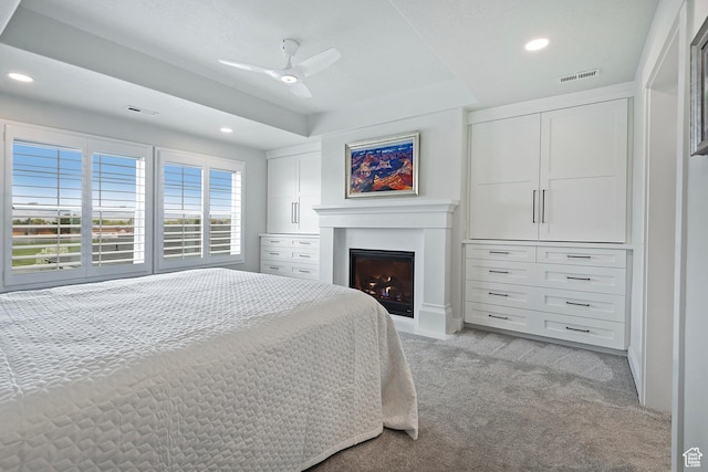bedroom with a lit fireplace, visible vents, recessed lighting, and light colored carpet