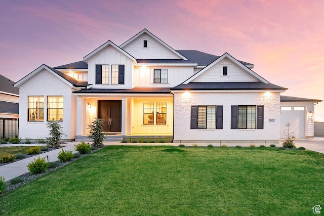modern farmhouse with board and batten siding, driveway, covered porch, and a front yard