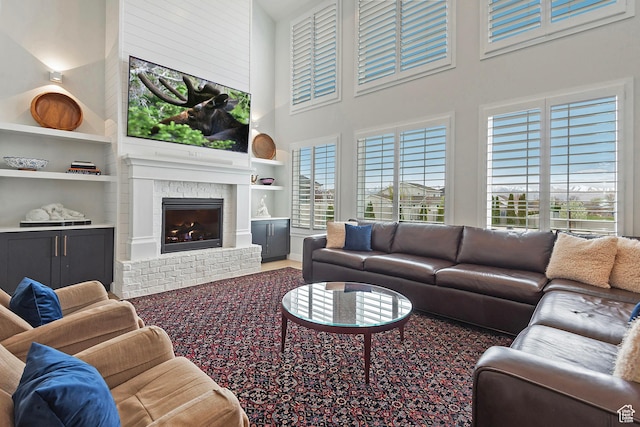 living room with a fireplace, built in features, and a towering ceiling