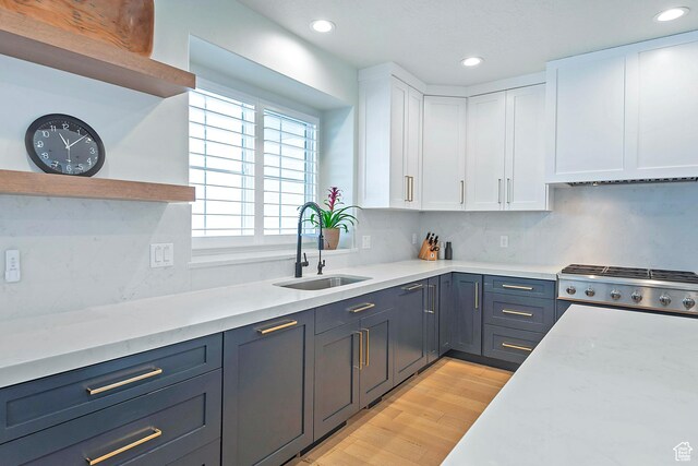 kitchen with a sink, decorative backsplash, light wood-style flooring, white cabinetry, and recessed lighting
