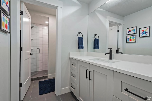 bathroom with baseboards, vanity, tile patterned floors, and a stall shower