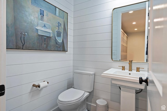 half bathroom with wood walls, recessed lighting, and toilet
