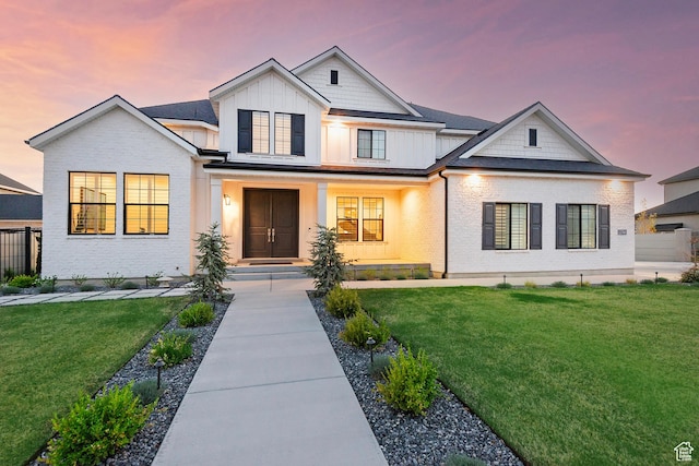 view of front of property featuring brick siding, fence, board and batten siding, and a front yard