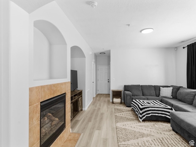 6939 S Tourist Ln W Unit 2C, West Jordan, UT 84084 - living area featuring arched walkways, a tile fireplace, and light wood finished floors