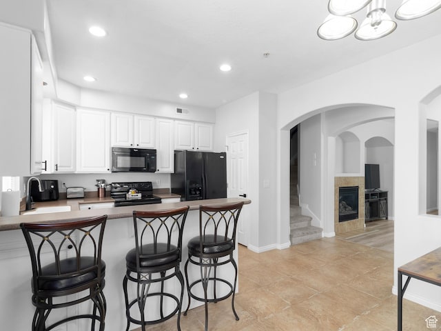 6939 S Tourist Ln W Unit 2C, West Jordan, UT 84084 - kitchen featuring a peninsula, a sink, visible vents, black appliances, and a breakfast bar area