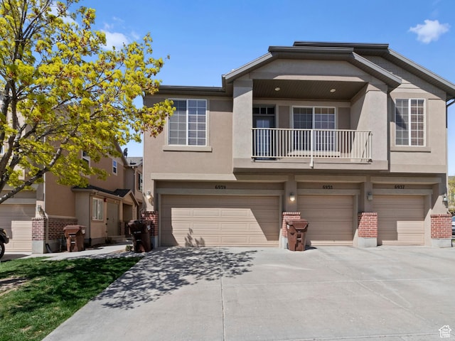 6939 S Tourist Ln W Unit 2C, West Jordan, UT 84084 - view of front facade with stucco siding, concrete driveway, a balcony, and a garage