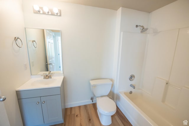 bathroom with toilet, bathtub / shower combination, baseboards, wood finished floors, and vanity