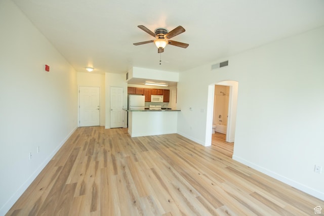 unfurnished living room with light wood finished floors, visible vents, a ceiling fan, arched walkways, and baseboards
