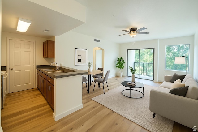 kitchen featuring dark countertops, a sink, open floor plan, light wood-type flooring, and visible vents