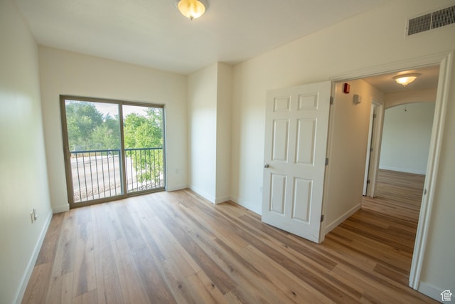 spare room featuring wood finished floors, visible vents, and baseboards