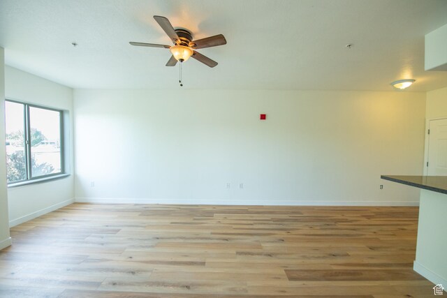 spare room featuring baseboards, a ceiling fan, and light wood-style floors