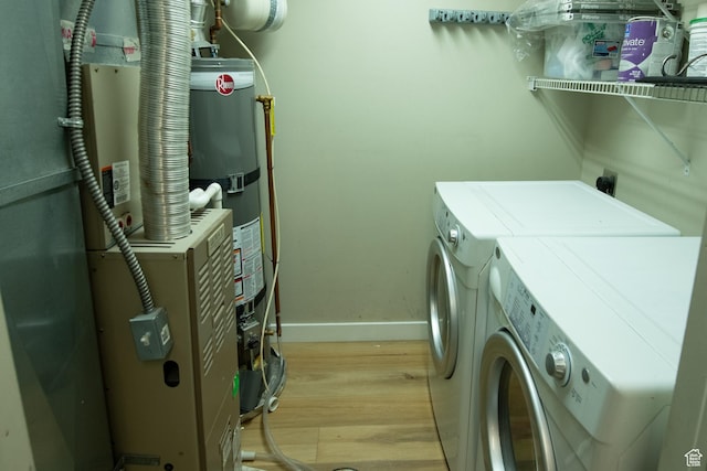 clothes washing area featuring washer and clothes dryer, light wood-type flooring, baseboards, secured water heater, and laundry area
