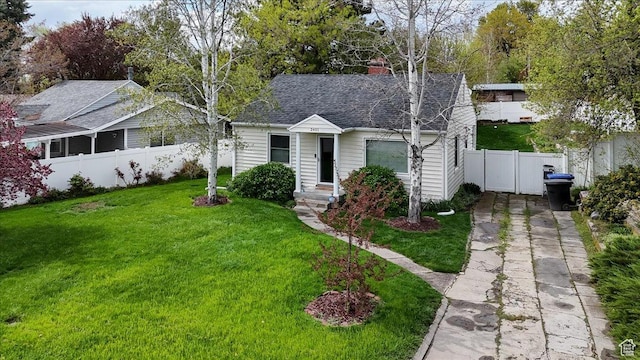 view of front of house with a front lawn, a chimney, concrete driveway, fence, and a shingled roof