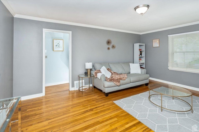 living room featuring baseboards, wood finished floors, visible vents, and ornamental molding