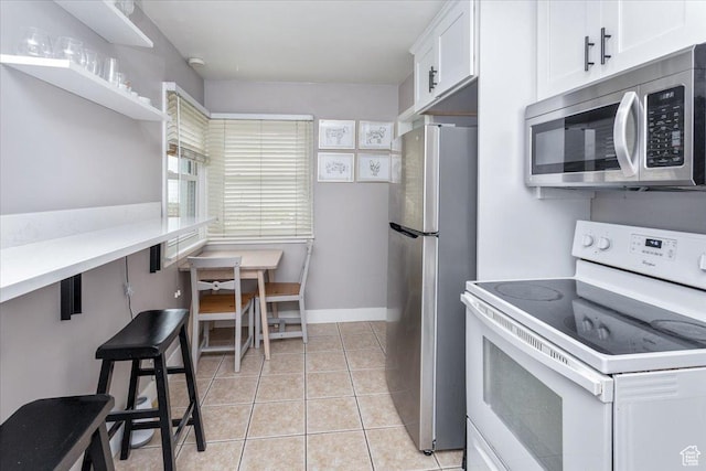 kitchen with white cabinets, light countertops, open shelves, light tile patterned floors, and appliances with stainless steel finishes