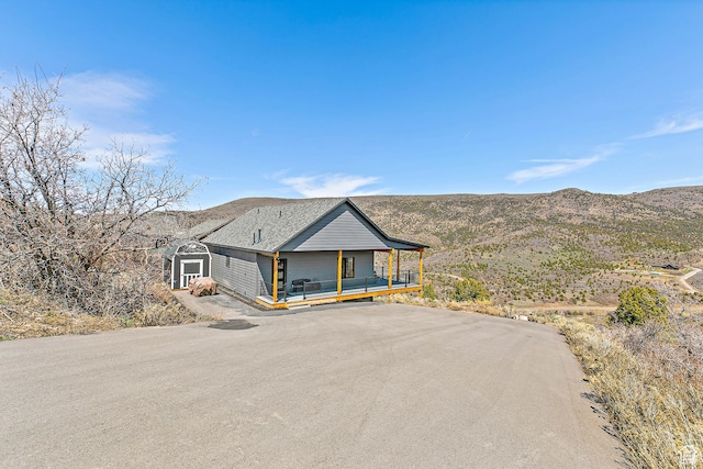 1678 S Ridgeline Dr Unit 1276, Heber City, UT 84032 - view of front of house featuring a shingled roof, an outdoor structure, a mountain view, a porch, and a storage unit