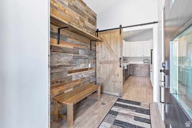 1678 S Ridgeline Dr Unit 1276, Heber City, UT 84032 - mudroom with a barn door, wooden walls, vaulted ceiling, and light wood-style flooring