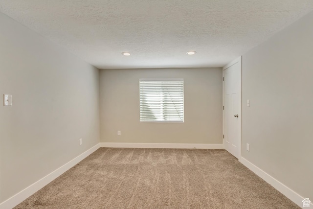 unfurnished room with carpet floors, baseboards, and a textured ceiling