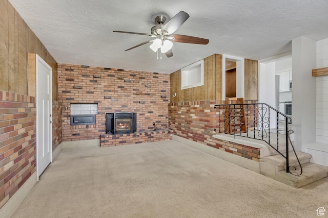 unfurnished living room with a textured ceiling, ceiling fan, carpet floors, and brick wall