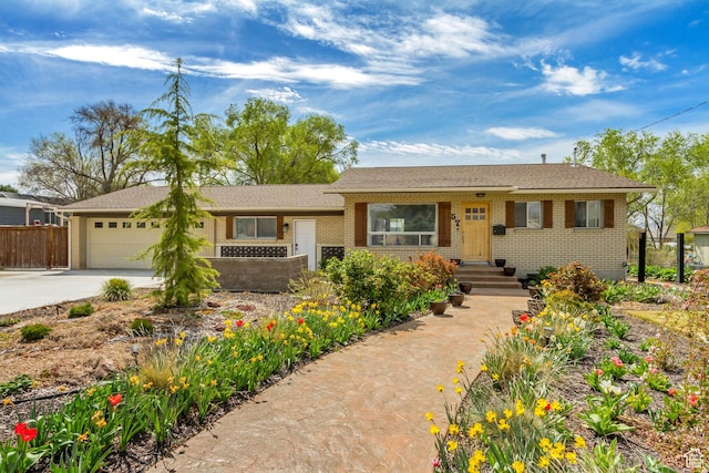 single story home with concrete driveway, an attached garage, brick siding, and fence