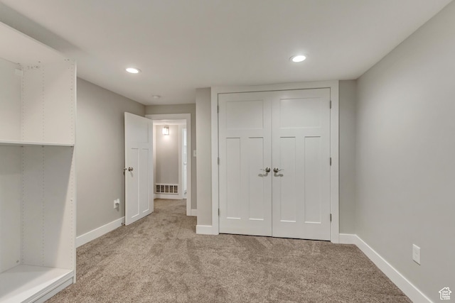 unfurnished bedroom featuring recessed lighting, visible vents, light carpet, a closet, and baseboards