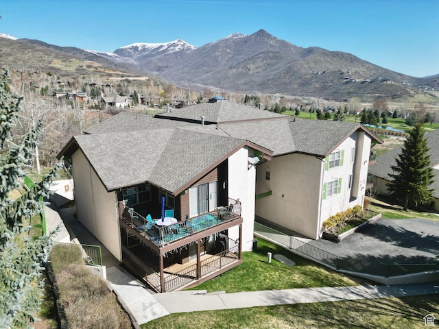 1004 Uri Ln, Midway, UT 84049 - rear view of house featuring fence, a shingled roof, a balcony, stucco siding, and a mountain view