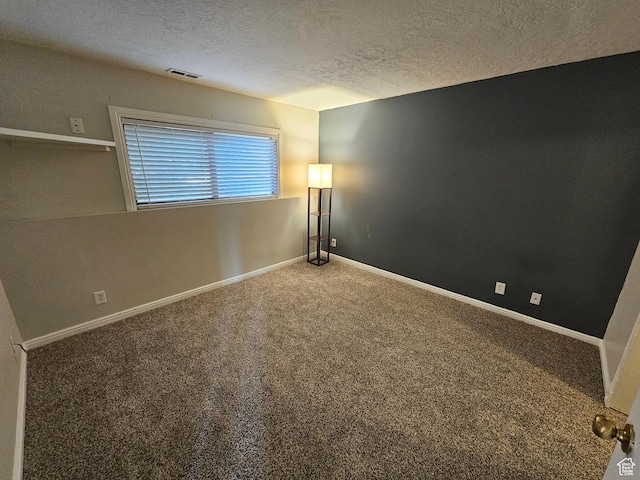 carpeted empty room featuring baseboards, a textured ceiling, and visible vents