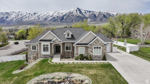 535 N Pheasant Hollow Ln, Mendon, UT 84325 - view of front facade with concrete driveway, a front lawn, stone siding, a mountain view, and fence