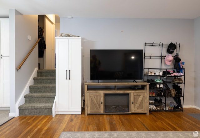 living area featuring baseboards, wood finished floors, and stairs