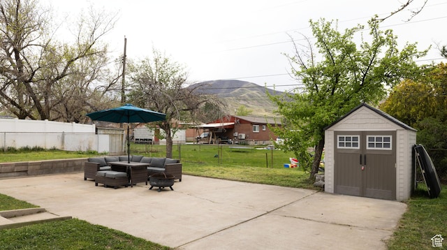 view of patio / terrace with a storage unit, an outbuilding, a mountain view, fence, and an outdoor living space