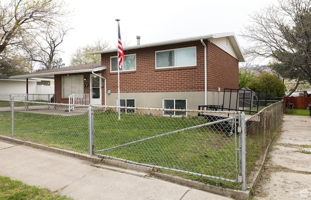 tri-level home with a gate, a front lawn, brick siding, and a fenced front yard