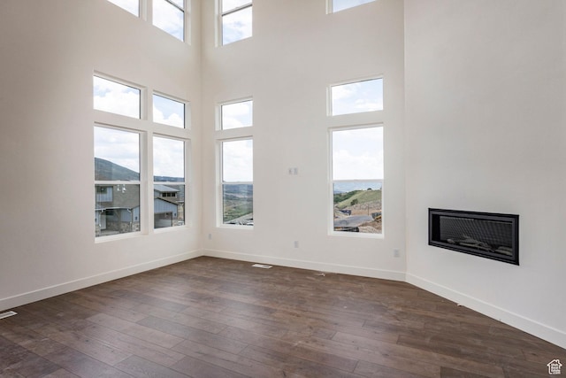 495 W Ascent Dr, Hideout, UT 84036 - unfurnished living room featuring dark wood finished floors, baseboards, a towering ceiling, and a fireplace