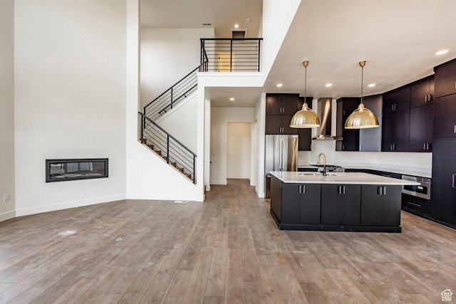 495 W Ascent Dr, Hideout, UT 84036 - kitchen featuring wall chimney exhaust hood, a sink, a center island with sink, light countertops, and appliances with stainless steel finishes
