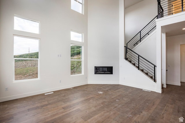 495 W Ascent Dr, Hideout, UT 84036 - unfurnished living room with dark wood finished floors, a high ceiling, a glass covered fireplace, and stairs