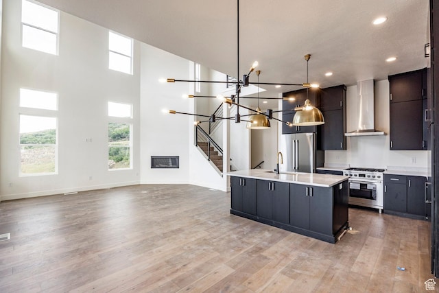 495 W Ascent Dr, Hideout, UT 84036 - kitchen featuring wall chimney exhaust hood, a kitchen island with sink, light wood finished floors, premium appliances, and light countertops