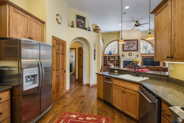 3270 E Rim Vistas Cir, Moab, UT 84532 - kitchen with stainless steel appliances, a sink, arched walkways, a ceiling fan, and brown cabinets