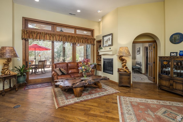 3270 E Rim Vistas Cir, Moab, UT 84532 - living area with a glass covered fireplace, arched walkways, wood-type flooring, a high ceiling, and visible vents