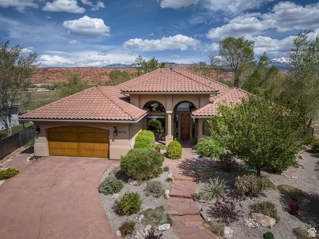 mediterranean / spanish-style house featuring a tile roof, driveway, fence, and a garage