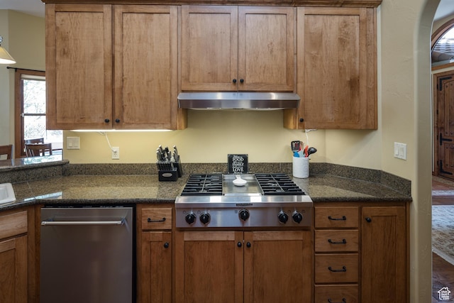 3270 E Rim Vistas Cir, Moab, UT 84532 - kitchen with stainless steel gas cooktop, brown cabinetry, and exhaust hood