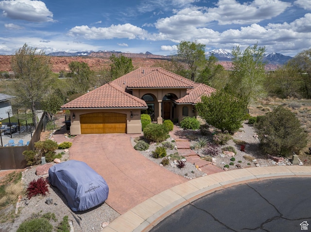 3270 E Rim Vistas Cir, Moab, UT 84532 - view of front of home with a tile roof, a mountain view, concrete driveway, an attached garage, and stucco siding